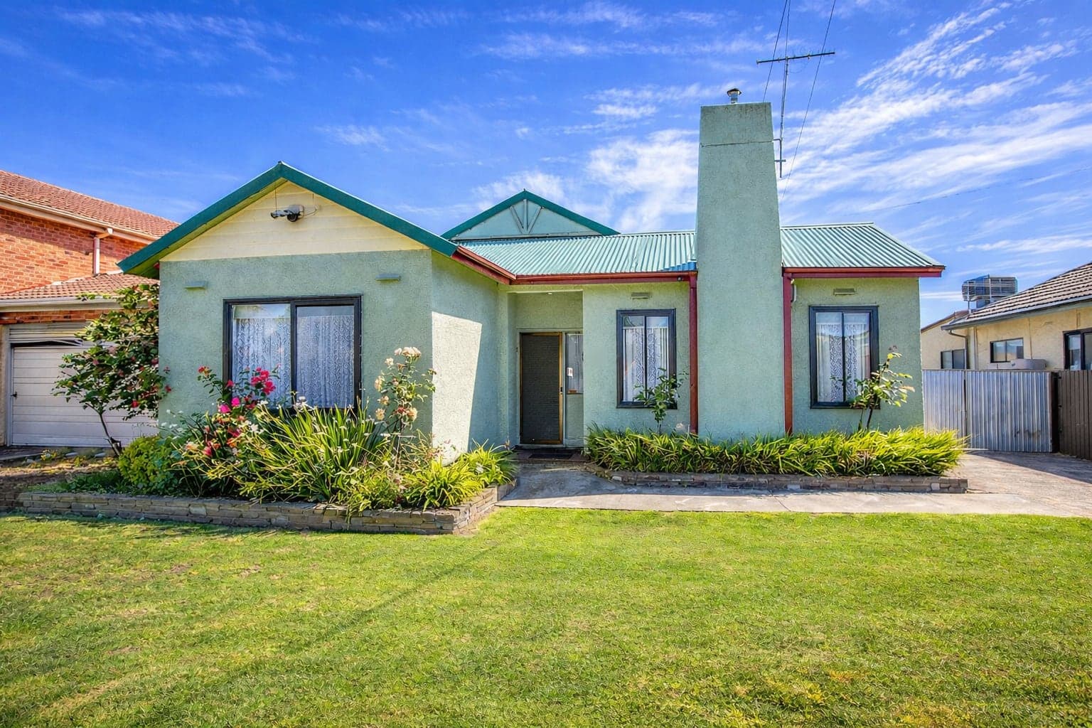 The front of the Albion home: a single-storey rendered house with a pitched metal roof, a front garden and a lawn.